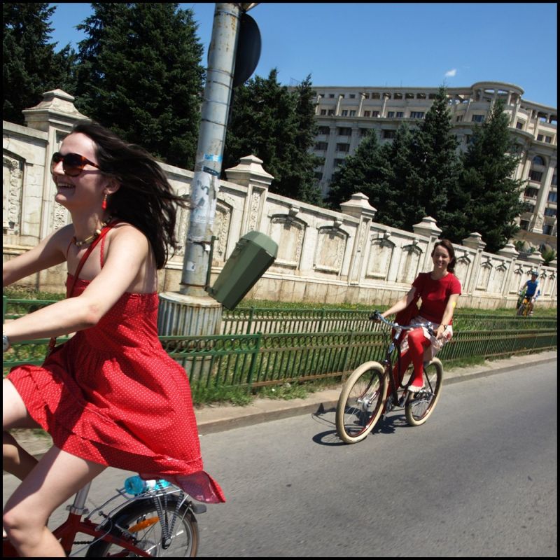 Cu tocuri şi rochie, pedalând pe bicicletă