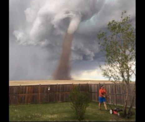 TORNADA îl bate pe umăr, dar acest bărbat este prea ocupat să tundă iarba