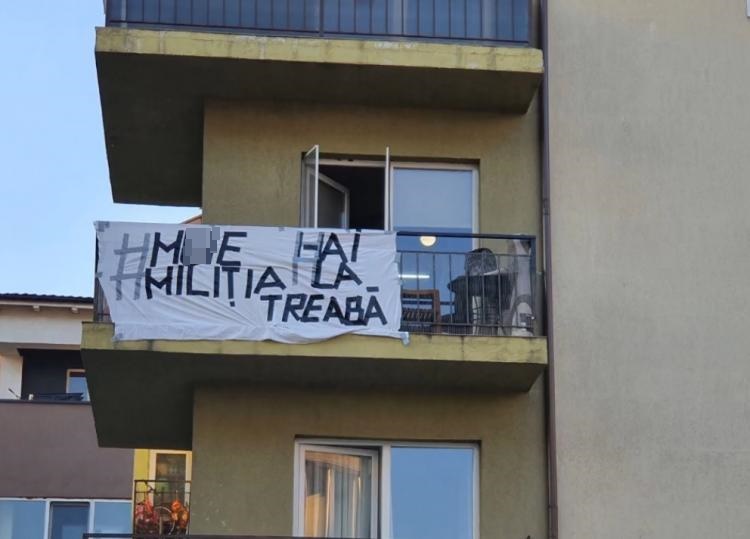 Luat pe sus de polițiști din propria casă! Ce mesaj a afișat un clujean de la balcon